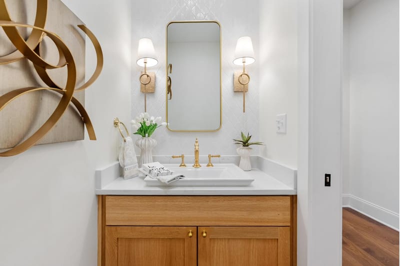 Powder room with an oak vanity, brass fixtures, and patterned wall tile