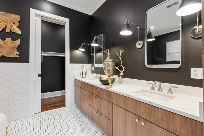 Primary bath with a walnut double vanity, marble counter, and black upper walls
