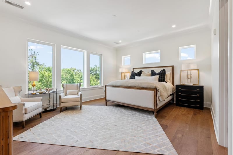 Primary bedroom with corner windows and an upholstered bed