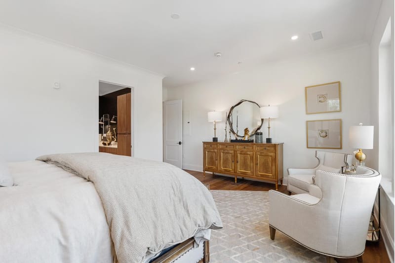 Bedroom looking toward a wood dresser and round mirror