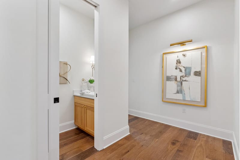 Hallway leading to the powder room, with framed art and oak floors