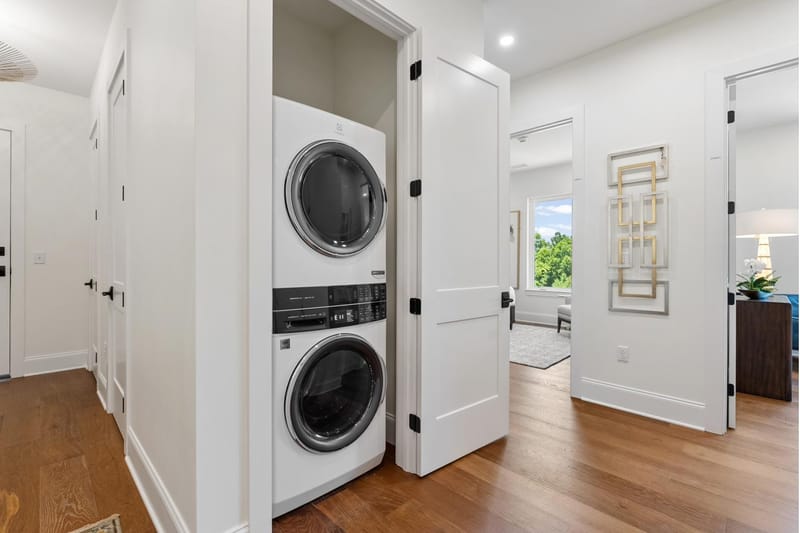 Laundry closet with a stacked washer and dryer off the hallway