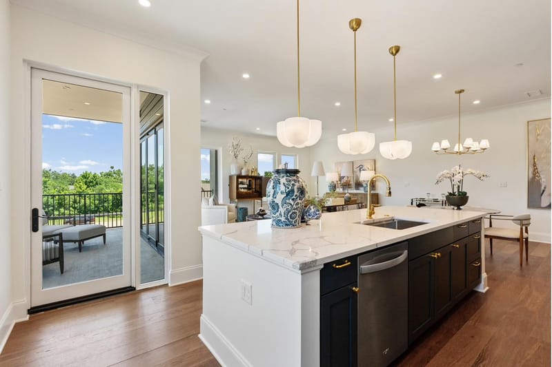 Kitchen island with marble counters and a brass faucet, looking toward the porch door