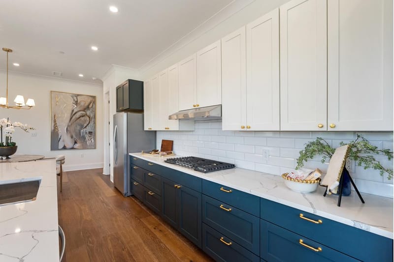 Kitchen run with navy base cabinets, white uppers, subway tile, and a gas cooktop