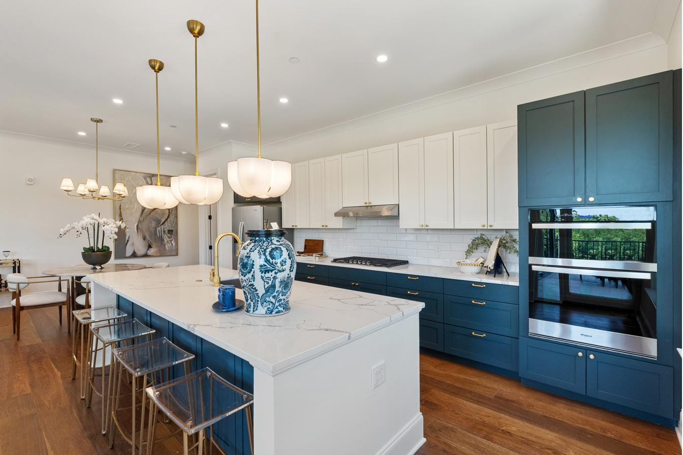 Kitchen at The Breakaway Oxford with double wall ovens set into navy cabinetry and seating at the marble island