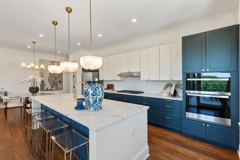 Kitchen with double wall ovens set into navy cabinetry and seating at the island