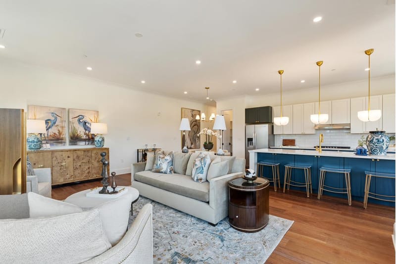 Open living room and kitchen with a navy island, brass pendants, and wide-plank oak floors