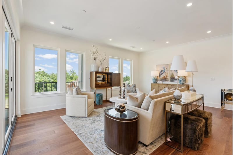 Living room seating area with a bar cabinet and a row of windows